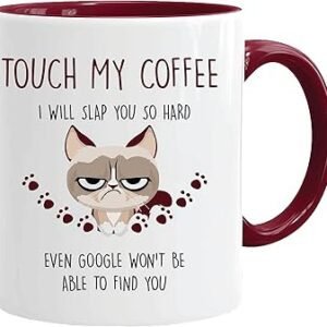 The Cat Mug - Touch My Coffee is designed with a maroon handle and interior and showcases a grumpy cartoon cat. It features the bold text, "Touch my coffee, I will slap you so hard even Google won't be able to find you," along with playful paw prints, bringing a humorous edge to your morning routine.